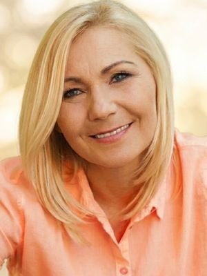 Maria Montero - Vidente y Tarotista Retrato de la vidente y tarotista Maria Montero sonriendo, con una blusa color melocotón, sobre un fondo desenfocado en tonos claros y cálidos.